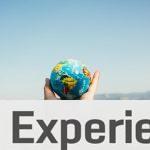 Person Holding World Globe Facing Mountain