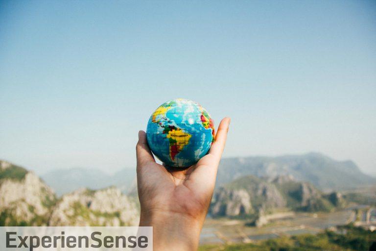 Person Holding World Globe Facing Mountain