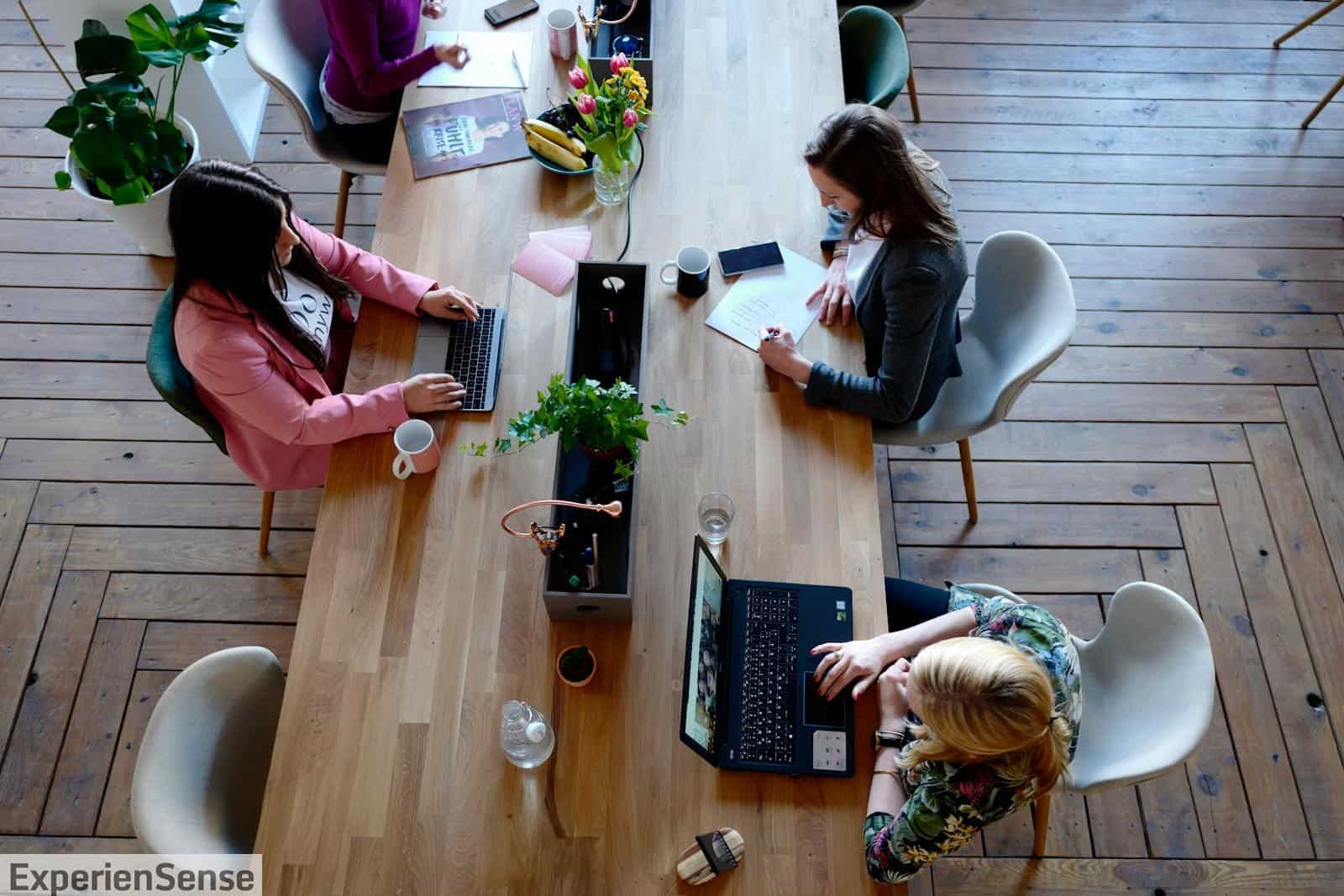 Three Woman Sitting on White Chair in Front of Table
