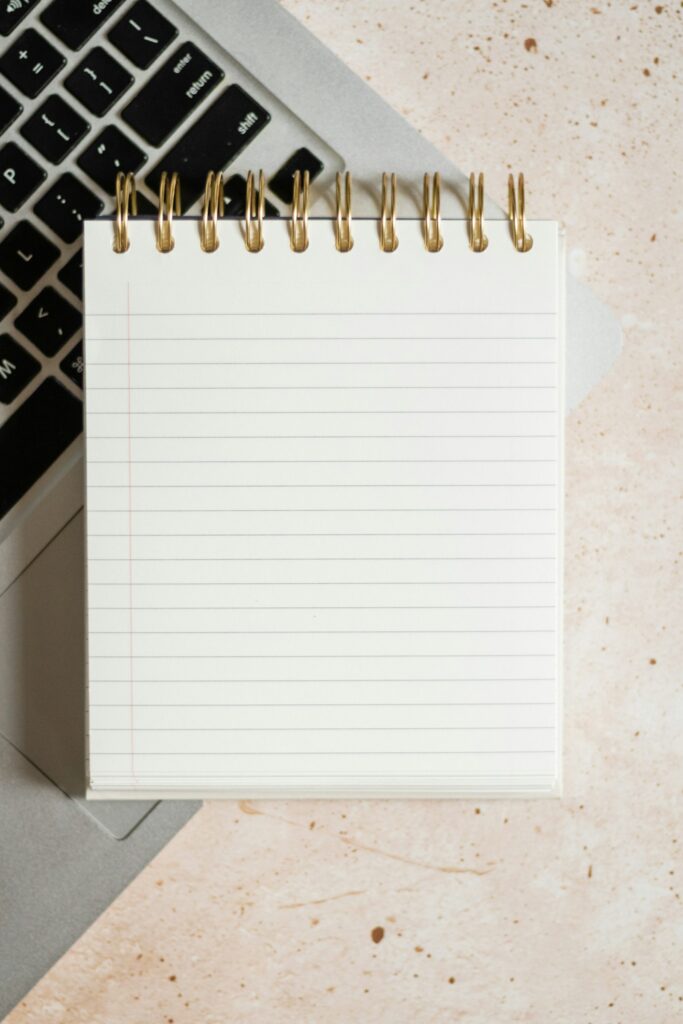 Bloc de notas apoyado sobre un portátil y un teclado